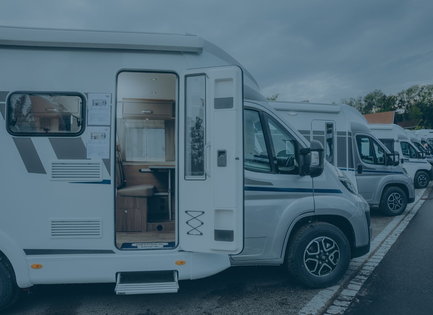 Carado motorhome in side view with the door open on a pitch, revealing a glimpse of the interior