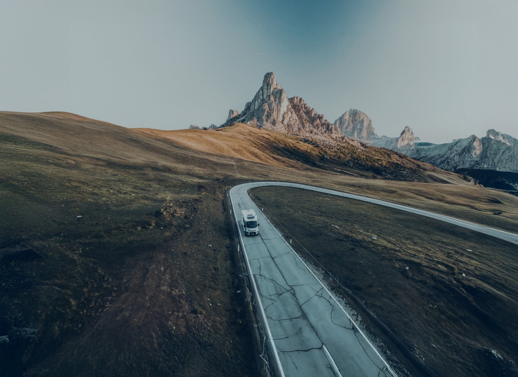 Carado camper op een kronkelende bergweg in een open hooggebergtelandschap