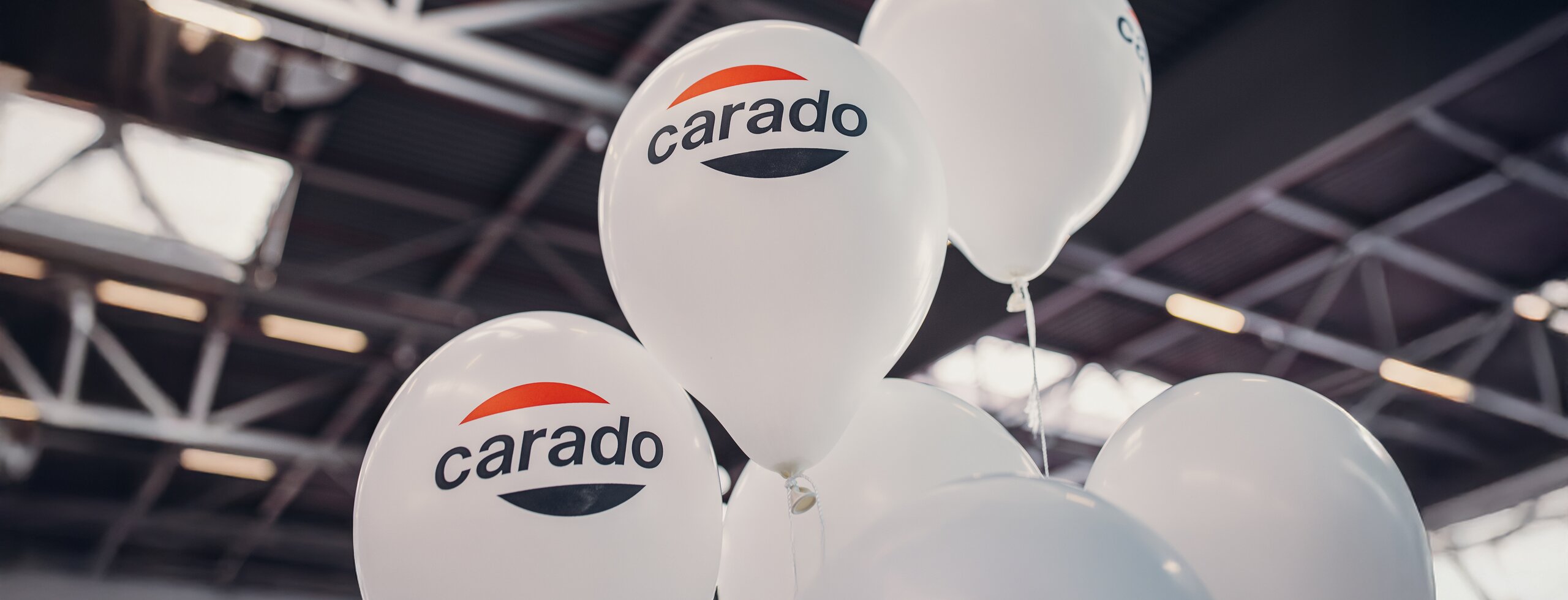 White balloons with the Carado logo in an exhibition hall