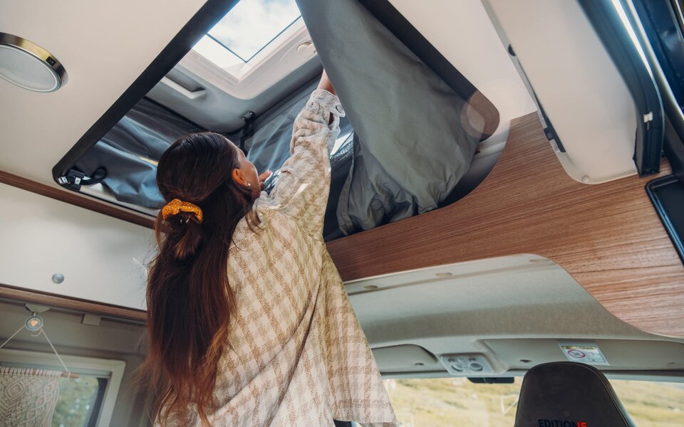 Person öffnet Dachbett im Carado Wohnmobil mit Blick auf Dachfenster