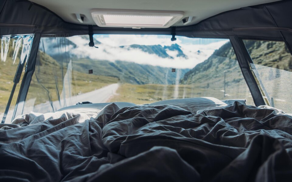 Blick aus dem Bett im Carado Wohnmobil auf Bergtal und Straße