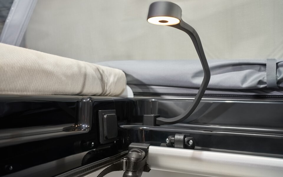 Leselampe am Bett im Carado Wohnmobil, Nahaufnahme von Matratze und Schlafbereich