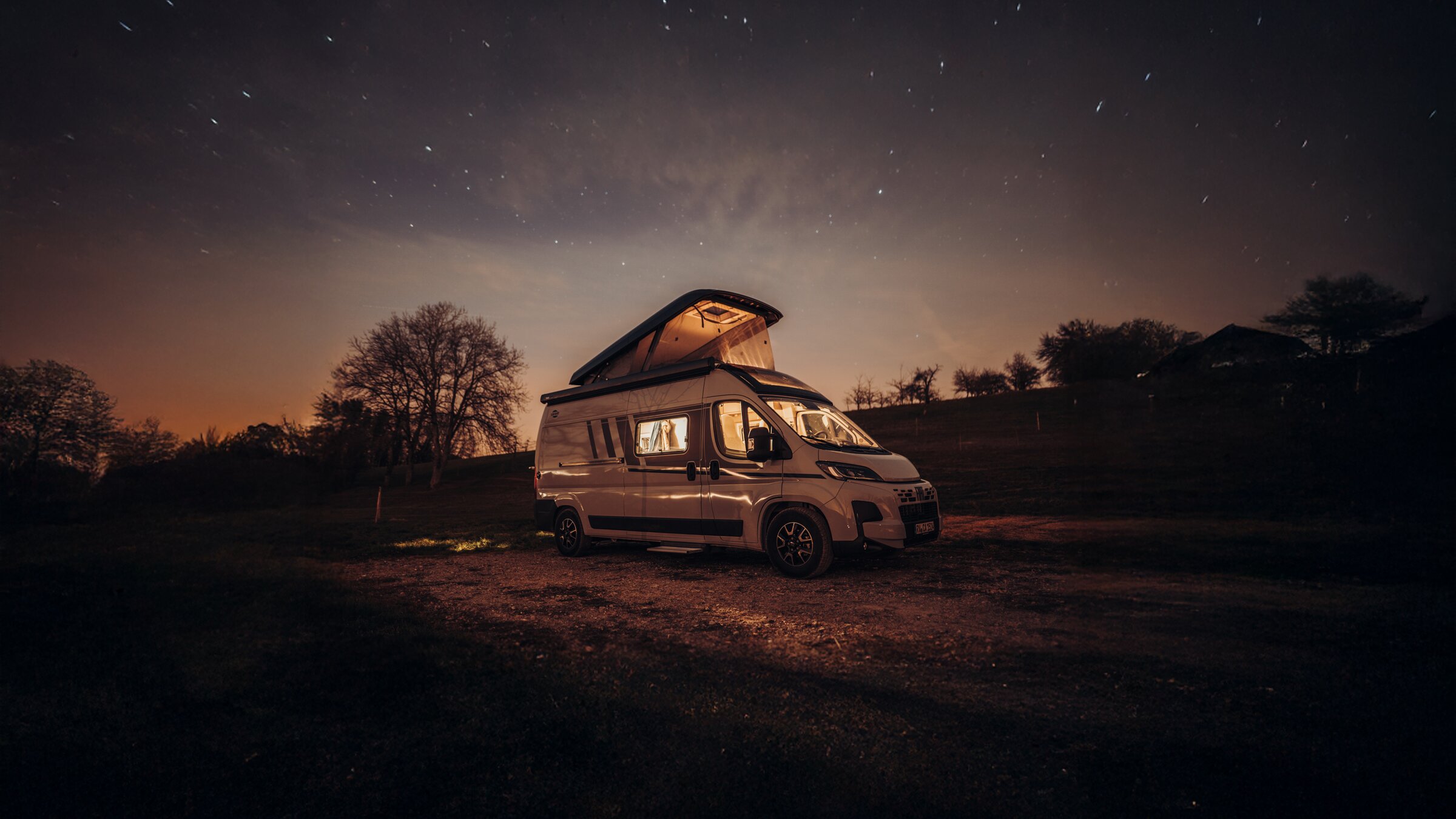 Carado motorhome with pop-up roof, parked overnight at a pitch under a starry sky