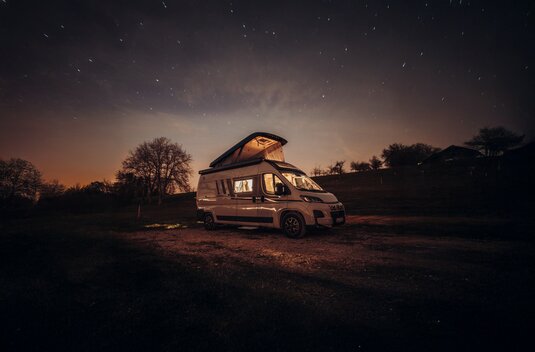 Carado motorhome with pop-up roof, parked overnight at a pitch under a starry sky