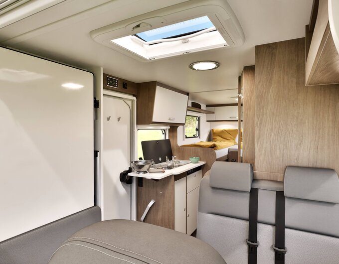 Carado motorhome interior with bench seat, kitchen unit, roof skylight and rear single beds