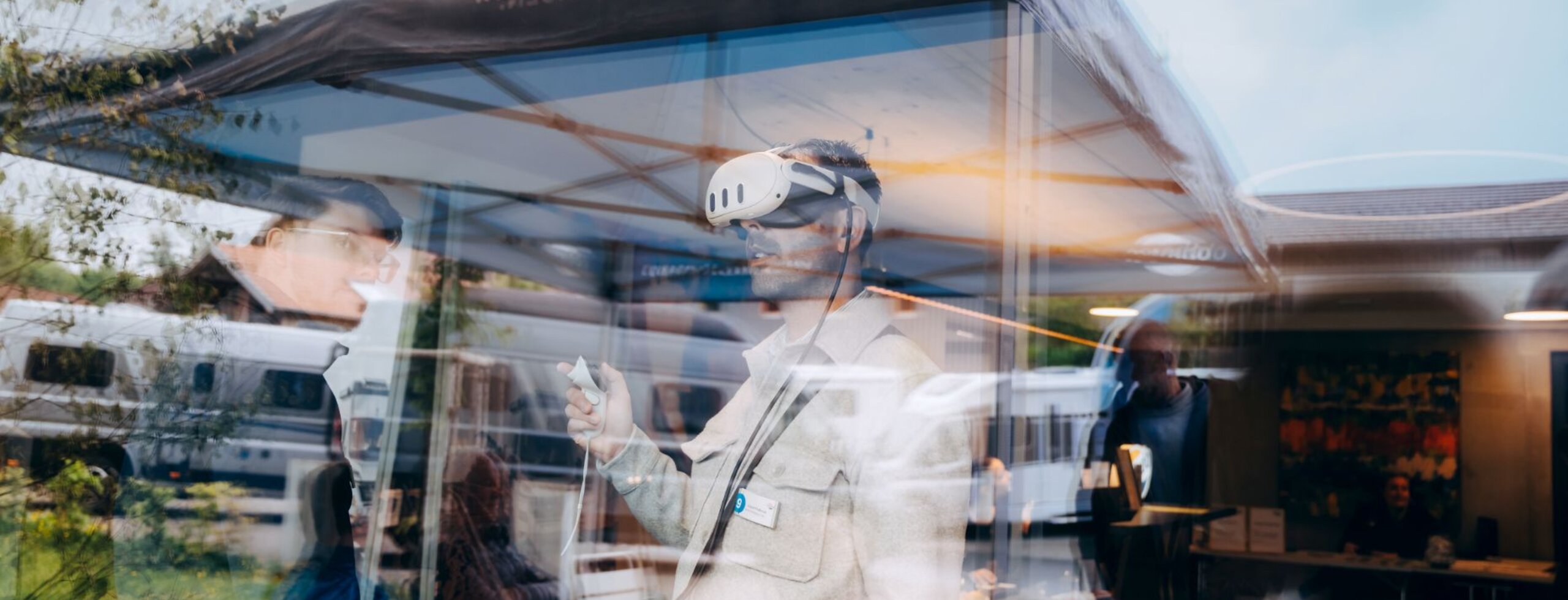 Person wearing VR glasses in an exhibition tent in front of Carado motorhomes