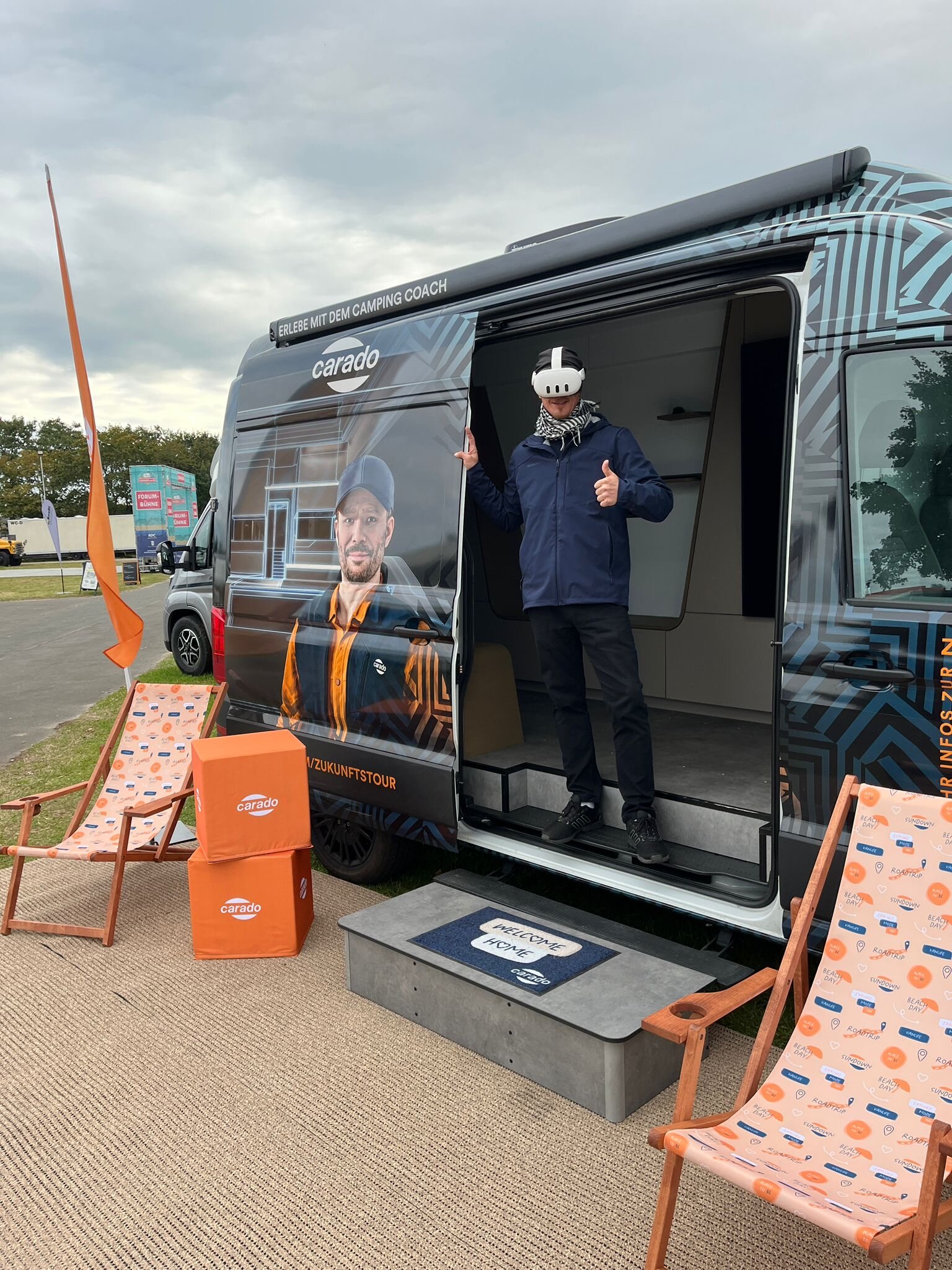 Person mit VR-Brille im Eingang eines Carado Campervan auf einer Messe