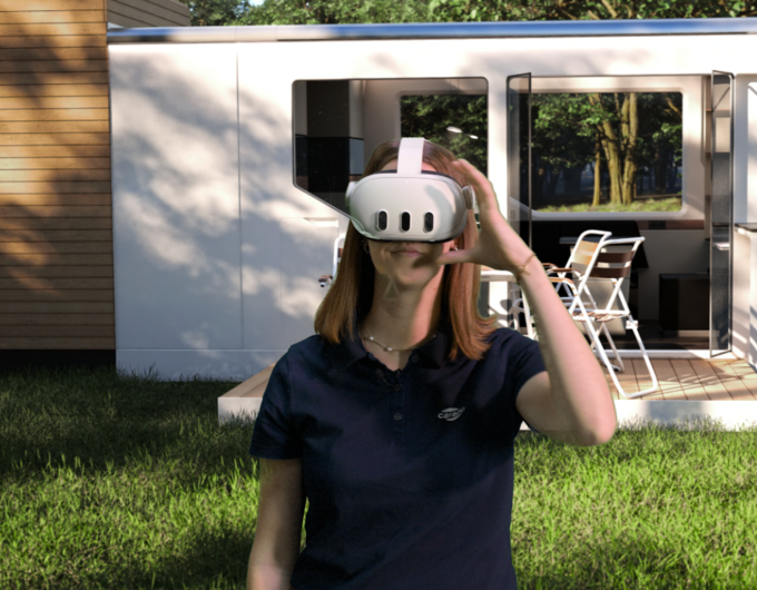 Person mit VR-Brille vor modernem Carado Wohnmobil auf Rasen, geöffnete Seitentür und Sitzgruppe im Hintergrund