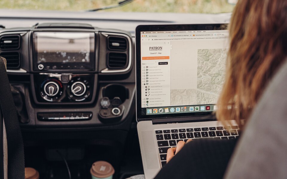 Person with a laptop in the cockpit of a Carado motorhome, map view on the screen