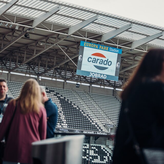 Carado logo on a video cube at Europa-Park Stadium, people blurred in the foreground