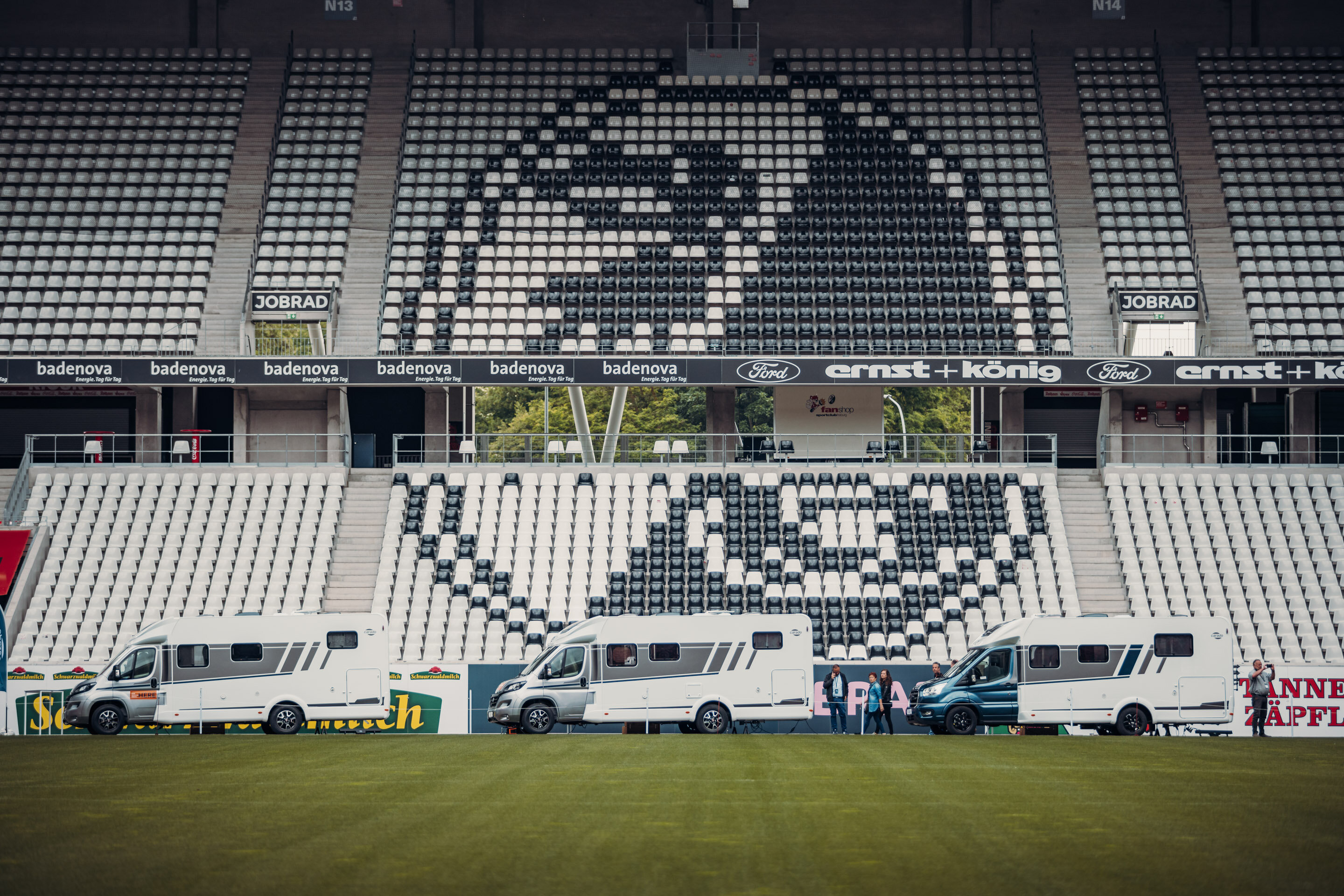 Three Carado motorhomes are parked pitchside in front of the stands of a football stadium.