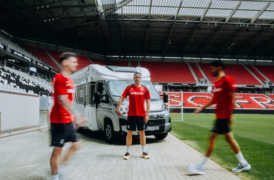 Carado motorhome at the football stadium, player with a ball in front