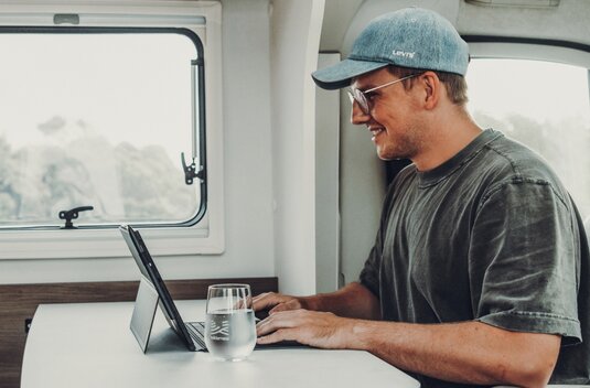 Man working on a tablet at the table in a Carado motorhome