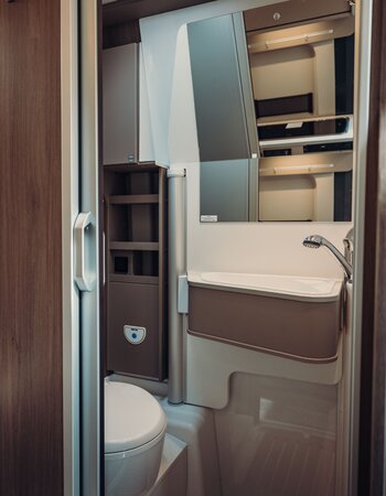 Carado motorhome bathroom with washbasin, mirror and toilet next to the sleeping area