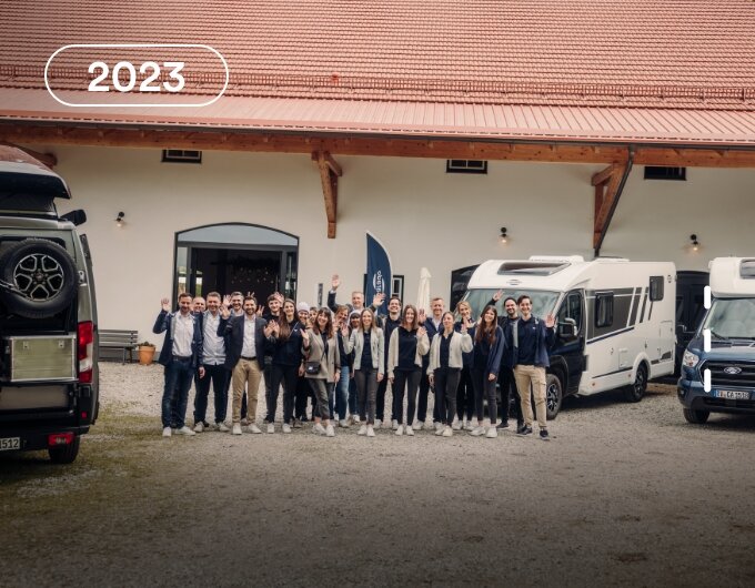 Group of people in front of Carado motorhomes in a courtyard by a building, 2023
