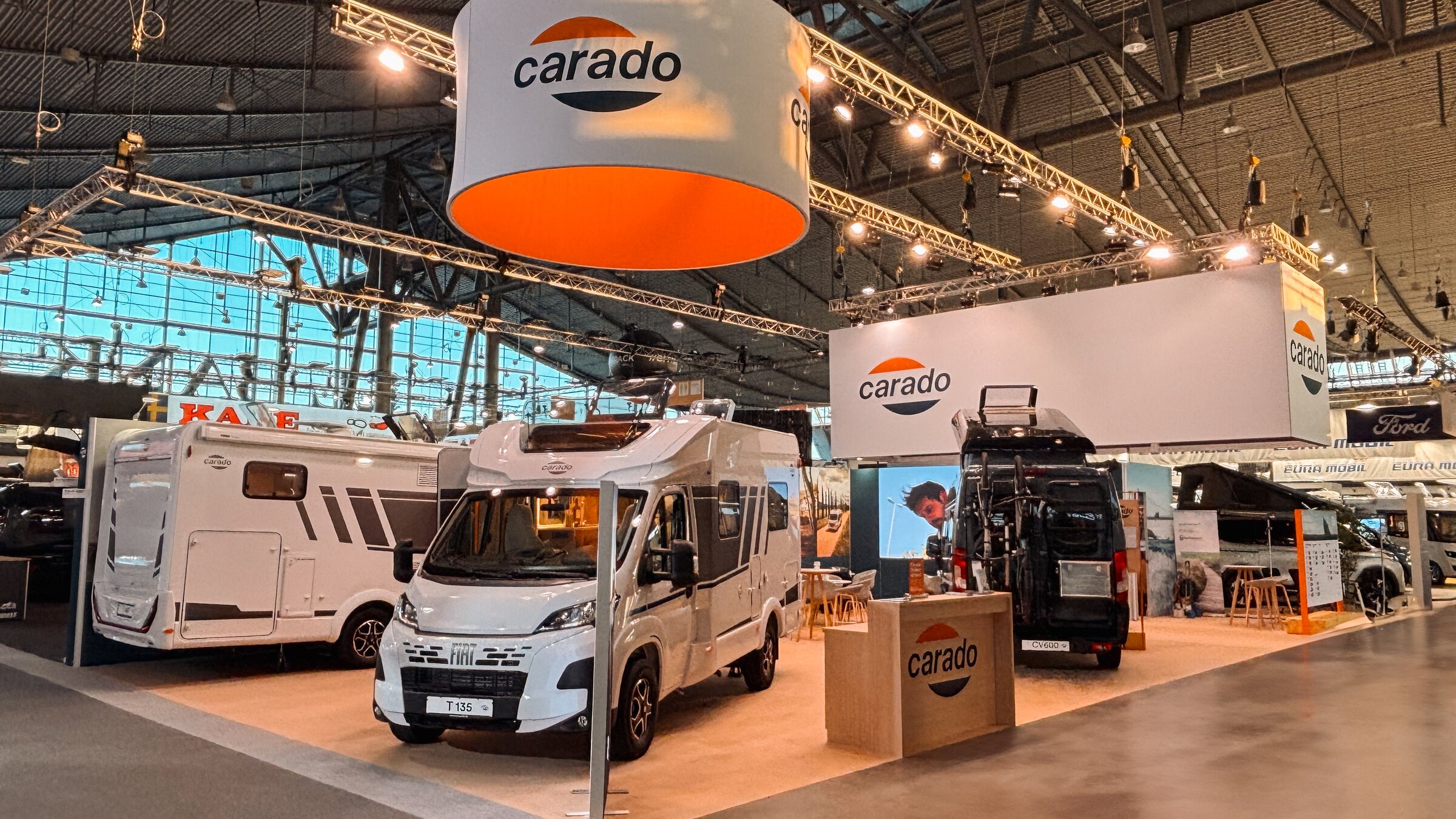 Carado Messestand mit teilintegrierten Wohnmobilen und Campervan in Messehalle