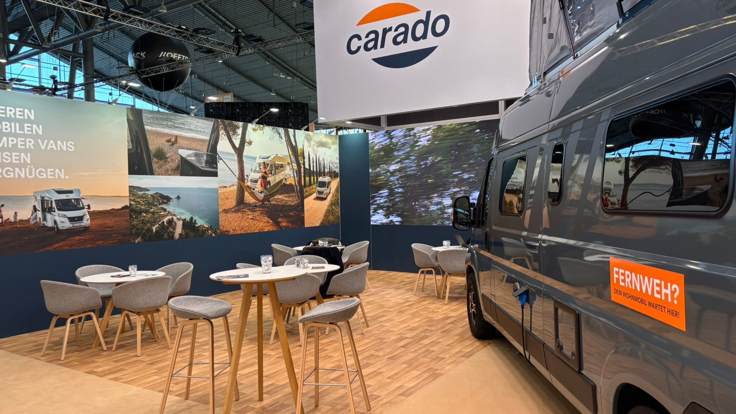 Carado Messestand mit Campervan, Sitzgruppe und großem Markenlogo in Messehalle