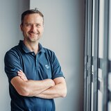 Man in a Carado polo shirt, arms crossed by the window