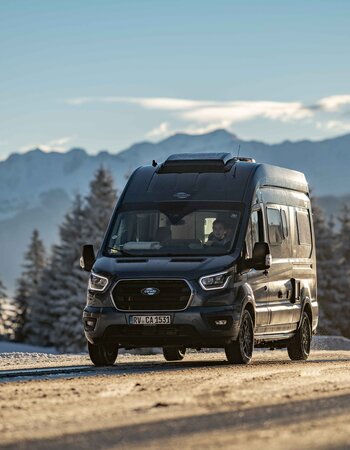 Carado motorhome seen from the front on a winter road with snow-covered mountains in the background