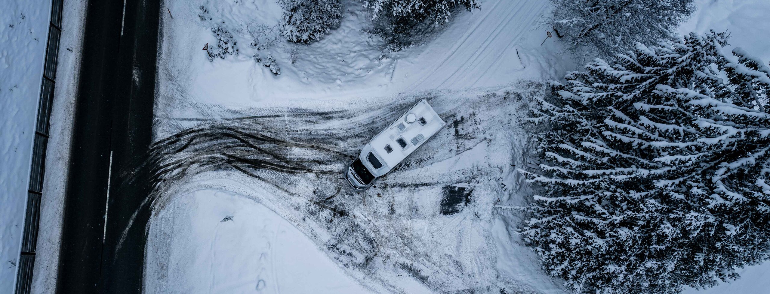 Carado motorhome seen from above on a snow-covered forest driveway near the road