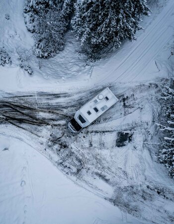 Carado motorhome seen from above on a snow-covered road at the edge of the forest