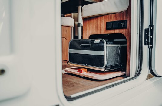 Pull-out storage compartment in the Carado motorhome with black bag under the seat bench at the entrance