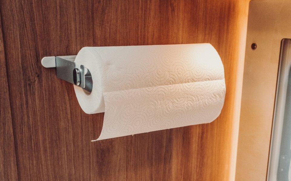 Paper towel roll on a metal holder mounted to a wooden panel in a Carado motorhome