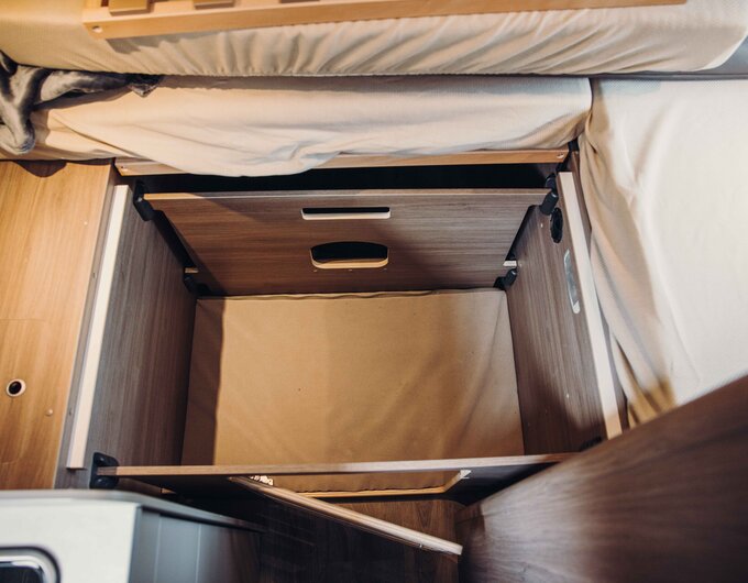 Open storage space under the bed in the Carado motorhome with wooden cladding