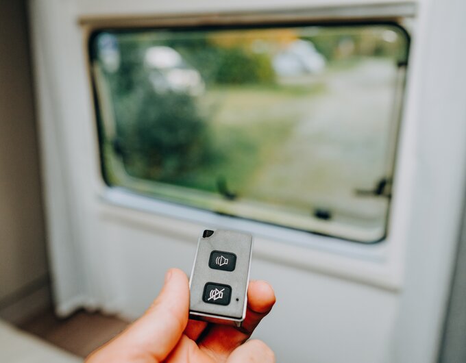 Hand holding a remote control in front of the motorhome window, inside the vehicle
