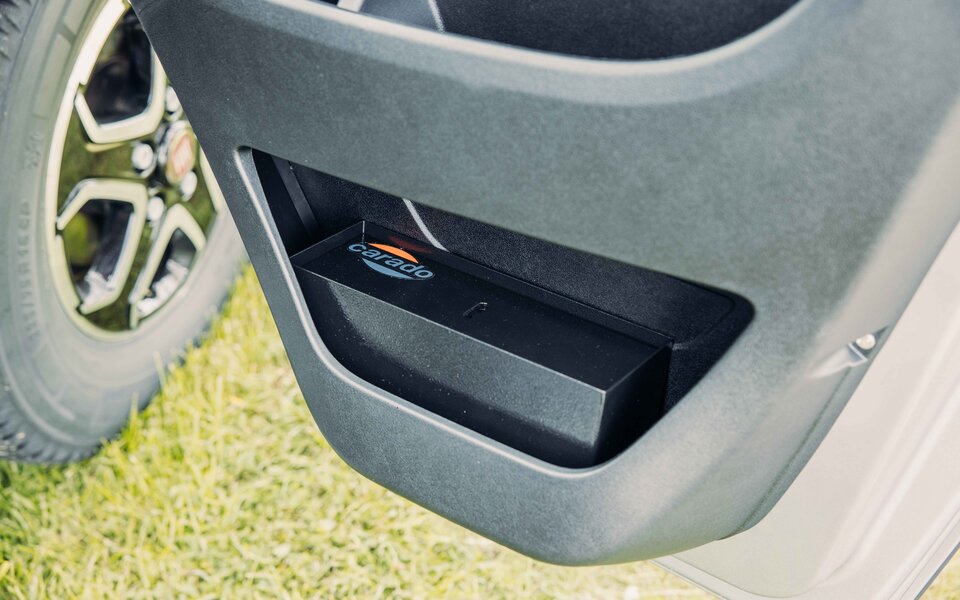 Storage compartment in the door of a Carado motorhome, close-up with a wheel in the background