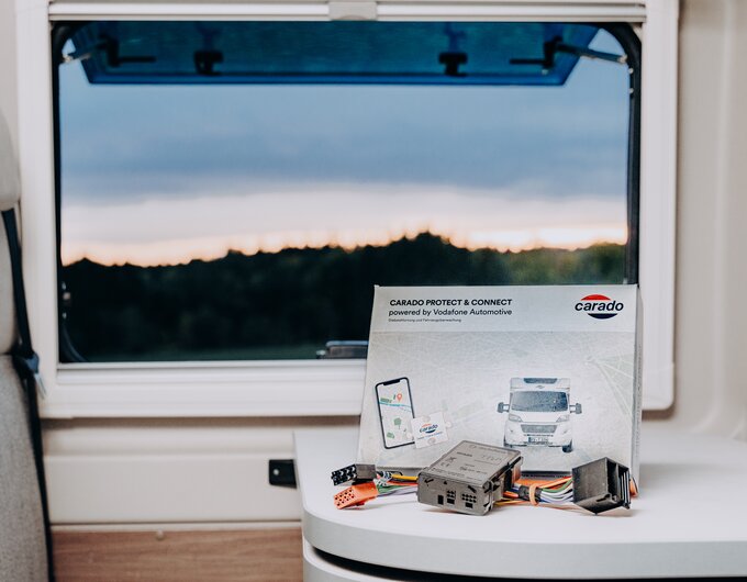 Carado Protect & Connect Box with cables and instructions on a table in the motorhome in front of a window