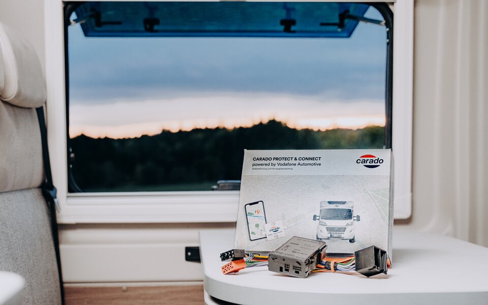 Carado Protect & Connect Box with cables and instructions on a table in the motorhome in front of a window