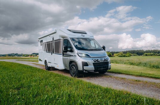 Camping-car Carado sur base Fiat sur un chemin de campagne, vue trois quarts dans un cadre rural