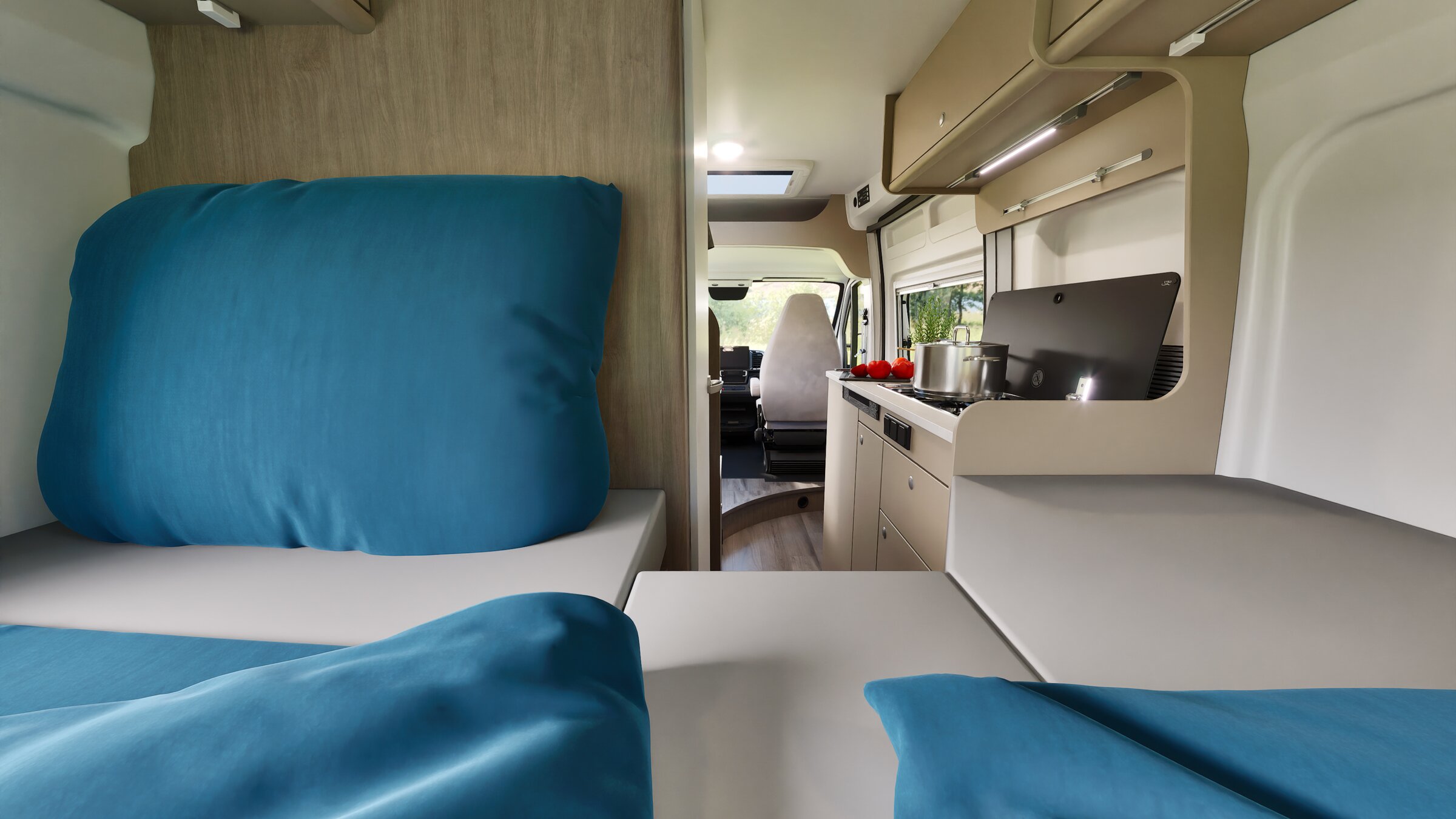 Interieur van de Carado-camper met achterbed, blauwe kussens en keuken met kookplaat, pan en bovenkasten