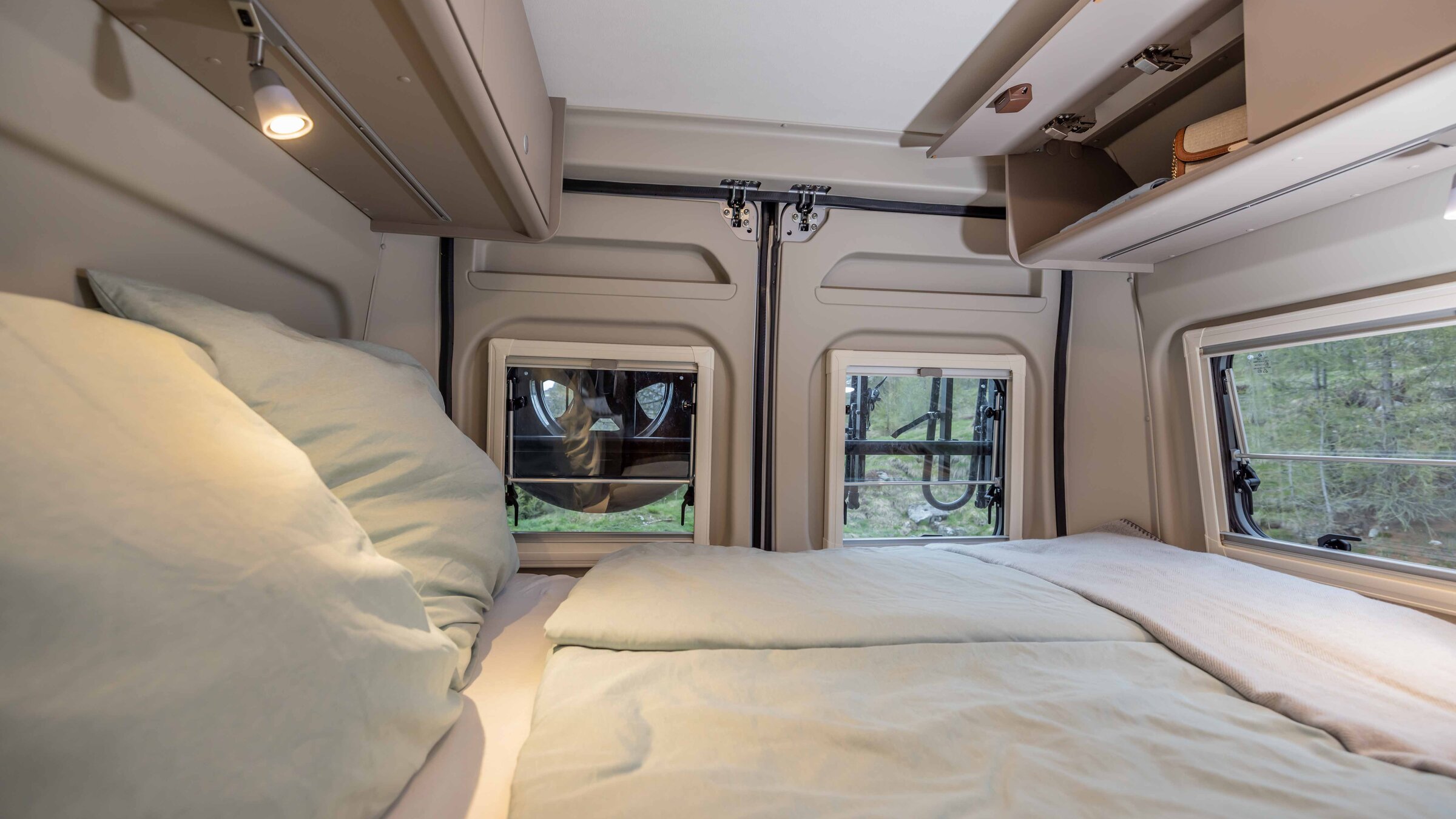 Slaapgedeelte in de Carado camper met tweepersoonsbed, bovenkasten en ramen achterin