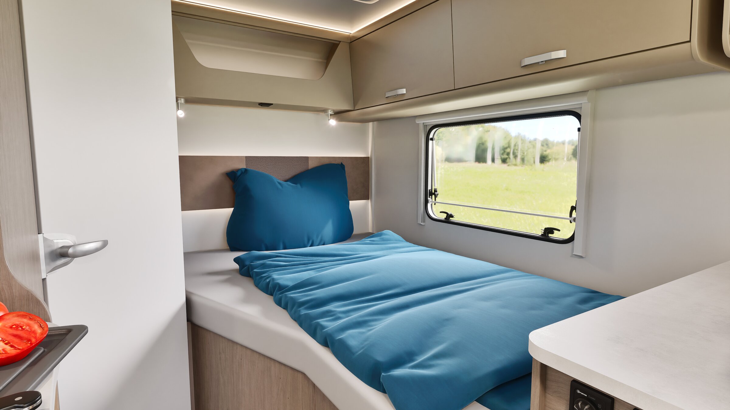 Slaapgedeelte in de Carado camper met eenpersoonsbedden, blauw beddengoed, bovenkasten en zijraam