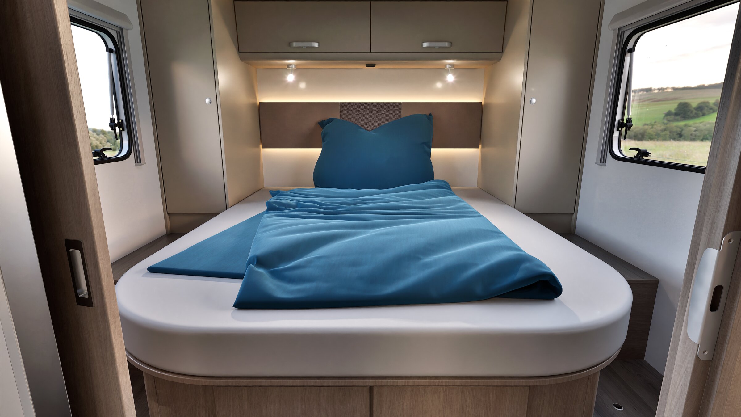 Slaapgedeelte in een Carado camper met tweepersoonsbed, bovenkastjes, leeslampen en zijramen