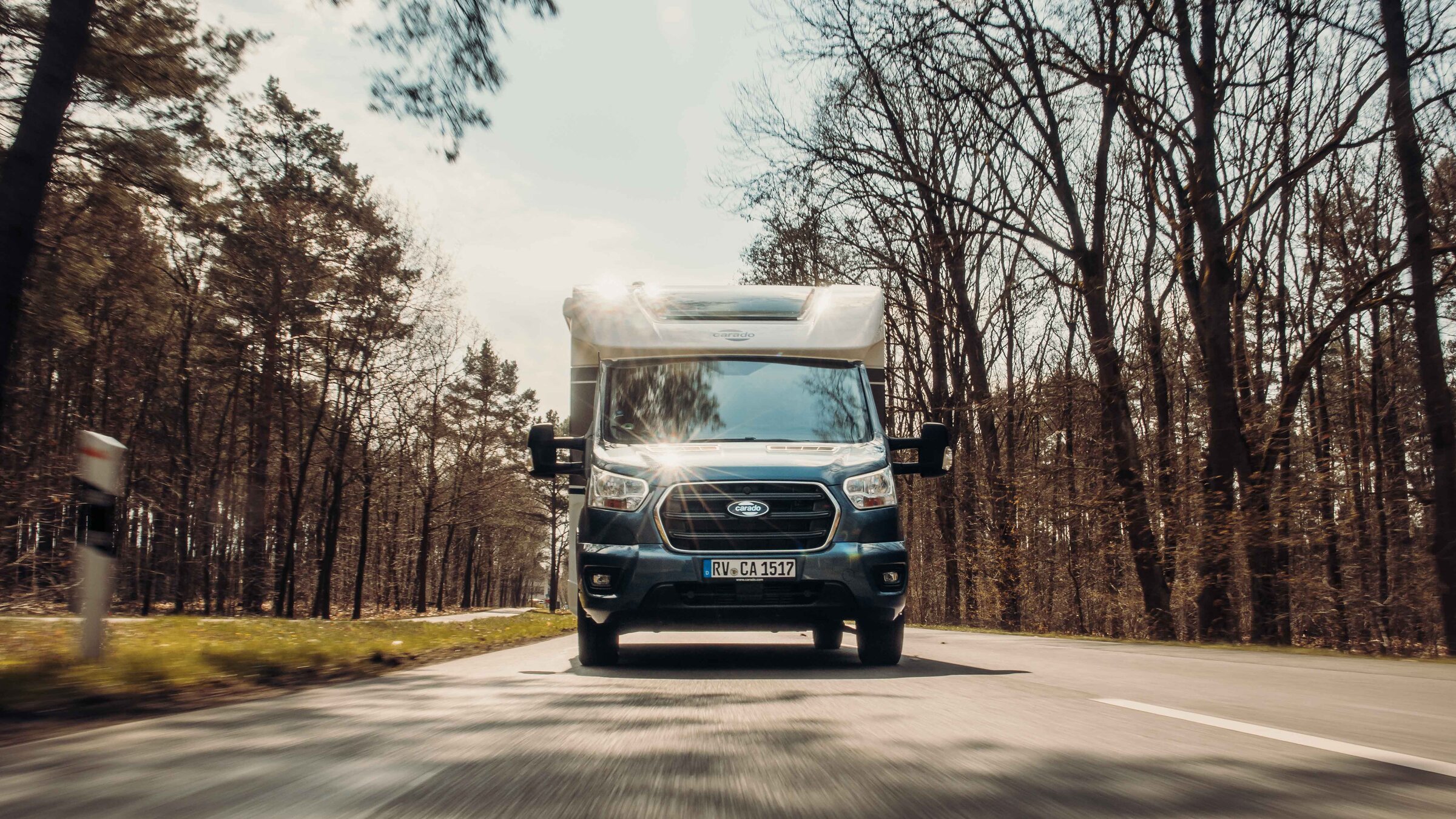 Carado motorhome from the front on a country road through the forest, with motion blur