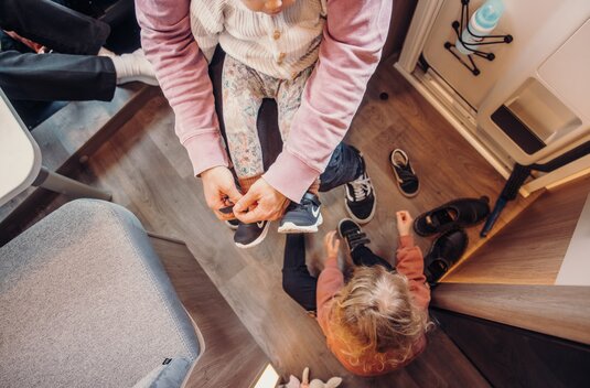 Entrance area in the Carado motorhome, with adults and children putting on their shoes