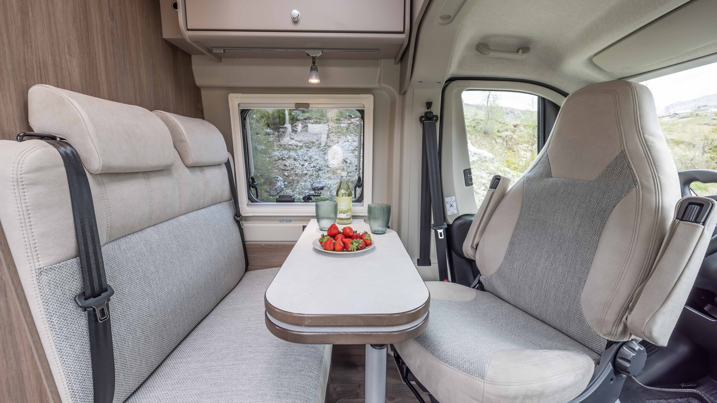 Coin salon dans le camping-car Carado avec table, banquette, siège avant pivotant et fenêtre