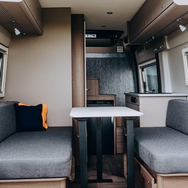 Carado motorhome interior with seating area, table, overhead lockers and kitchen unit