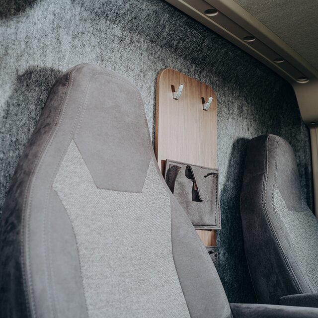 Carado motorhome interior with two front seats, wall hooks and storage pockets behind the seats