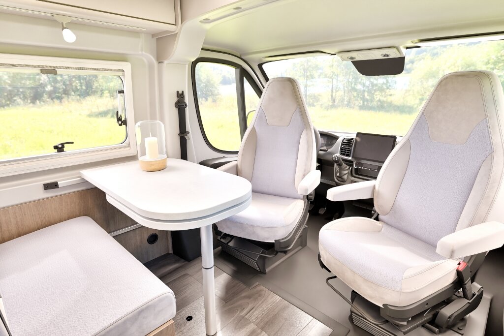 Carado motorhome interior with seating area, table and swivelling cab seats