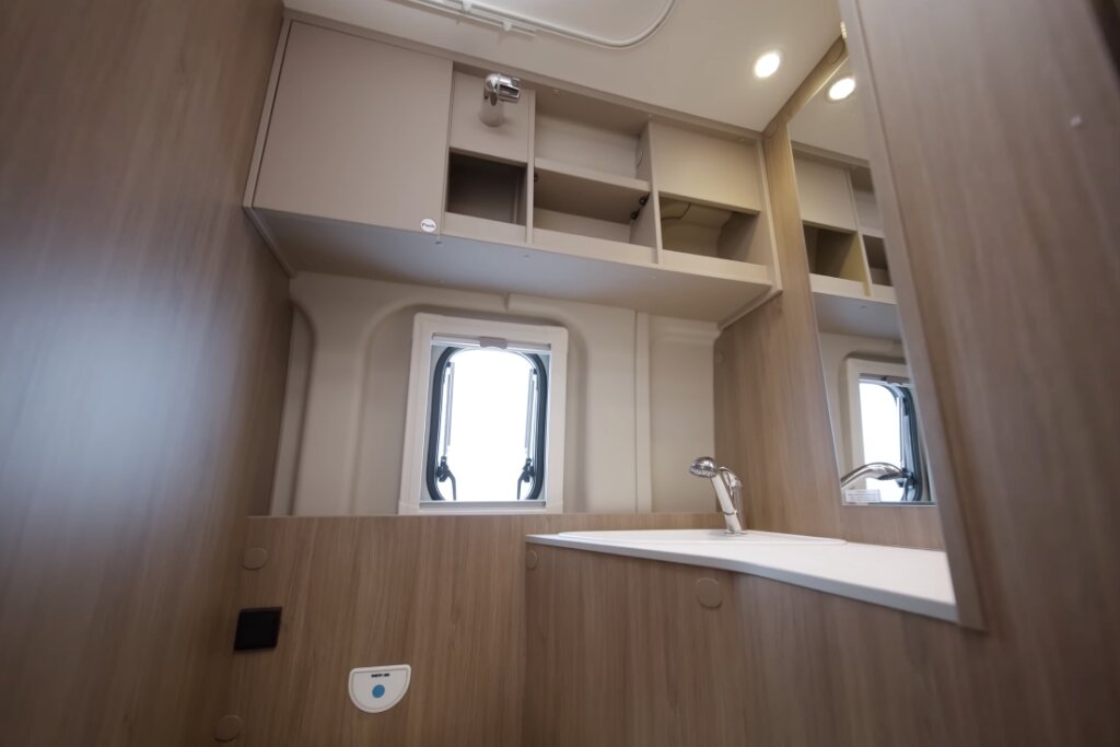 Bathroom in the Carado motorhome with washbasin, mirror, overhead lockers and window