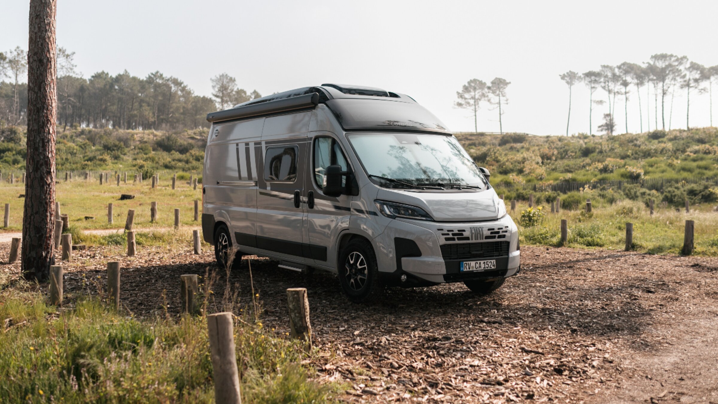 Carado camper van in three-quarter view on a natural pitch with trees and meadow