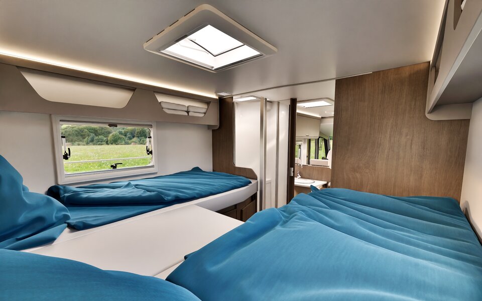 Sleeping area in the Carado motorhome with two single beds, roof window, side window and access to the bathroom