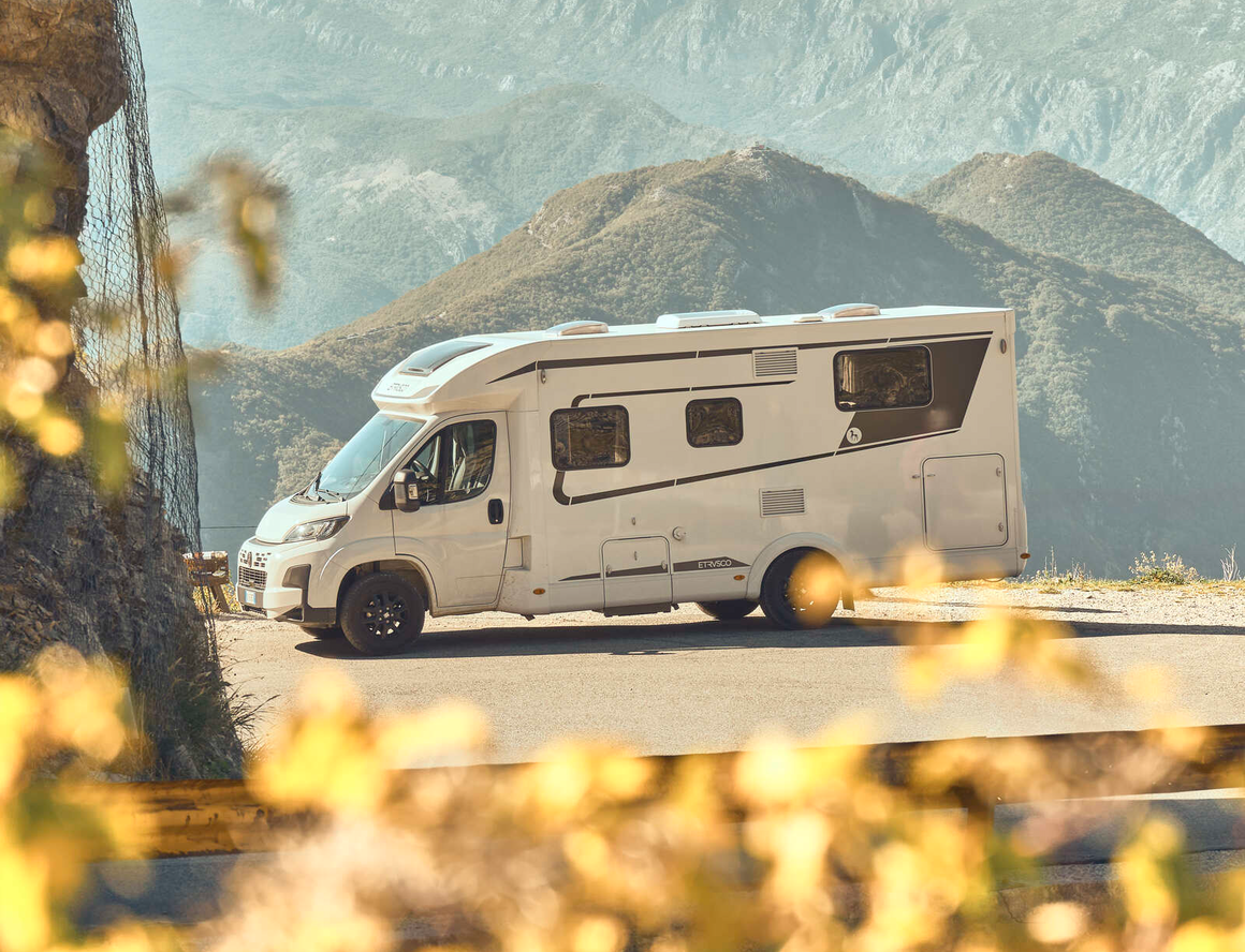 Teilintegriertes Fiat Wohnmobil von Etrusco steht im Hof eines italienischen Hauses, während eine Frau im Sommerkleid aussteigt.