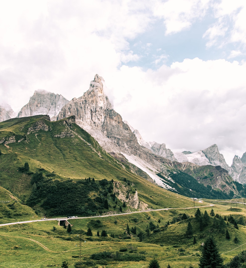 Mountain landscape with green hills, winding road, and peaks – perfect setting for nature-oriented camping trips.