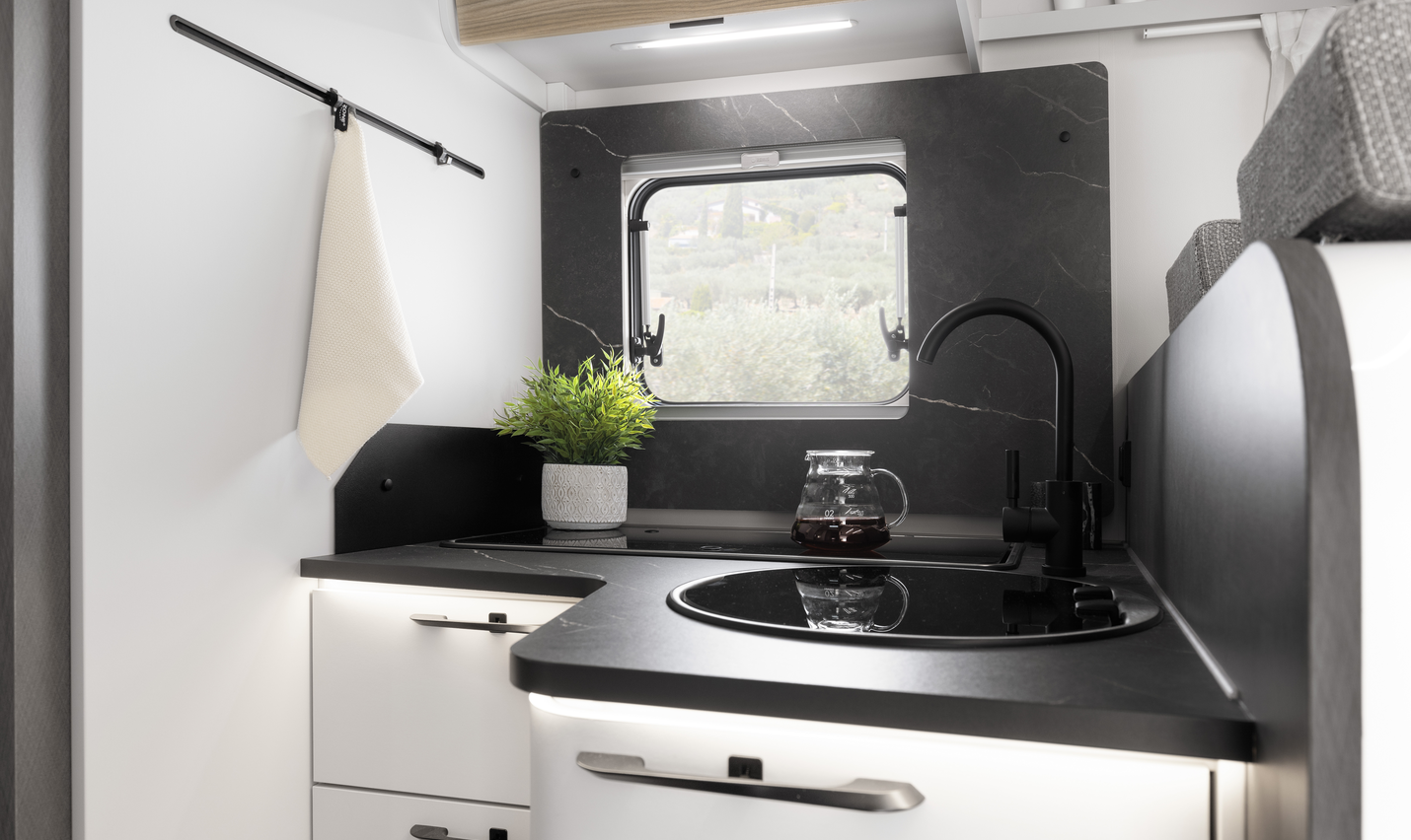 Kitchen area of an Etrusco semi-integrated Fiat motorhome with stainless steel sink, closed gas stove, and daylight through a window.