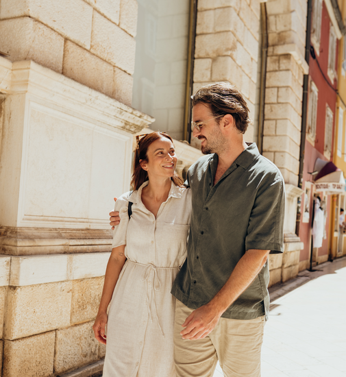 Relaxed couple enjoys coffee on a piazza at an Italian café as part of their camping trip.